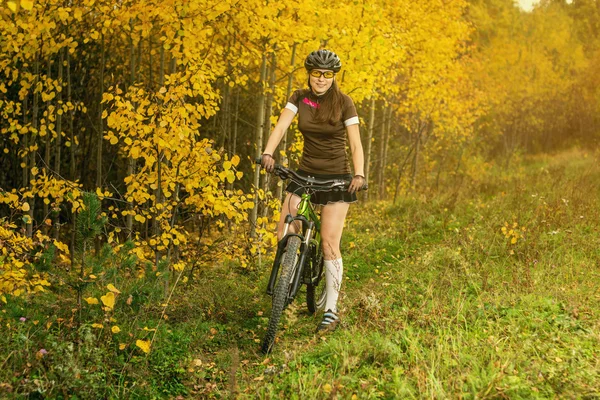 Femme faisant du vélo dans la forêt jaune d'automne sur une prairie — Photo