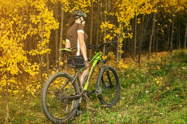 Femme faisant du vélo dans la forêt jaune d'automne sur une prairie — Photo