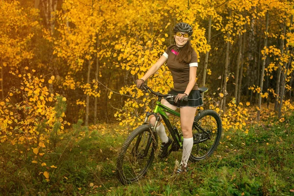 Femeie cu bicicleta în pădurea galbenă de toamnă pe o pajiște — Fotografie, imagine de stoc