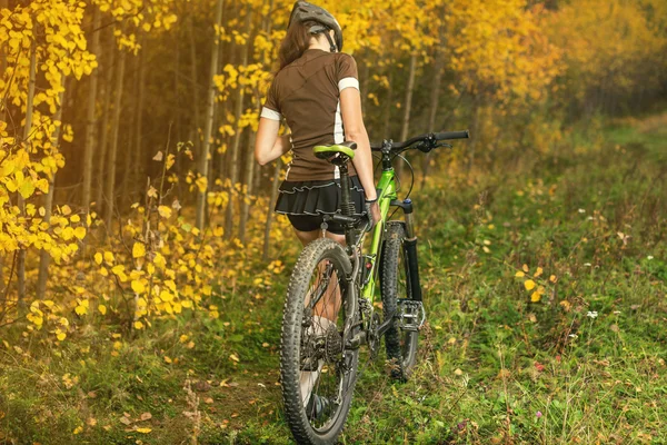 Woman biking in yellow autumn forest on a meadow — Stock Photo, Image