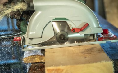 İşçi marangoz ahşap bir tahtayı el testeresiyle kesiyor. Yakın çekim..