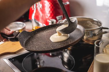 Bir insan hamuru sıcak tavaya döker ve lezzetli ev yapımı krepleri kızartır. Kendi mutfağında krep yapma kavramı..