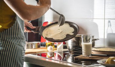 Bir insan hamuru sıcak tavaya döker ve lezzetli ev yapımı krepleri kızartır. Kendi mutfağında krep yapma kavramı..