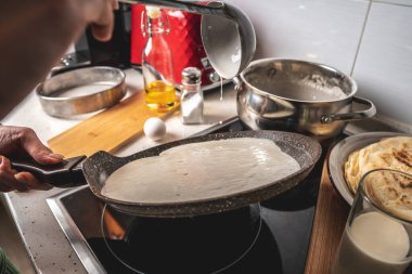 Kişi sıcak tavada krep pişiriyor. Evde lezzetli bir kahvaltı hazırlama süreci kavramı.