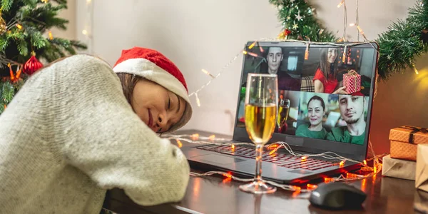 A young woman fell asleep in front of a computer screen while communicating with friends and relatives via video link. Concept for remote Christmas and new Year parties