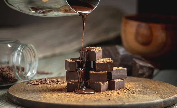 Heap of delicious cubes of bitter dark chocolate sprinkled with cocoa powder and poured with liquid chocolate.