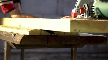 İşçi marangoz ahşap bir tahtayı el testeresiyle kesiyor.