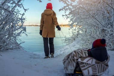 Güneşli bir günde, dondurucu bir kış sabahı çocuklu bir anne yürür. Battaniyeye sarılı bebek kızağa biniyor.