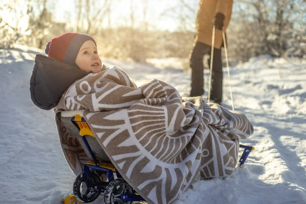 子供を持つ母親は晴れた日に霜の多い冬の朝を歩く そりに毛布に包まれた赤ちゃん — ストック写真