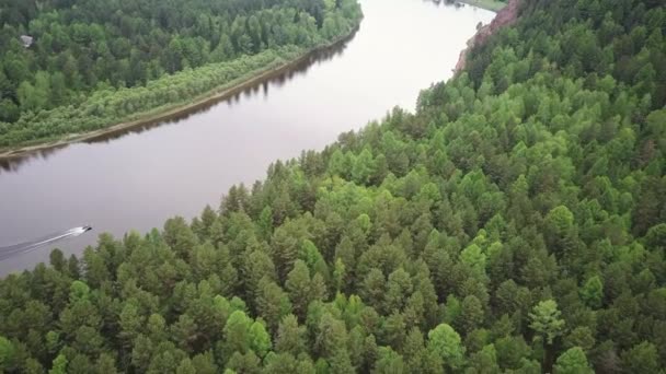 O barco flutua no rio entre muitas árvores verdes em tempo nublado. Bela vida selvagem da Sibéria do drone — Vídeo de Stock
