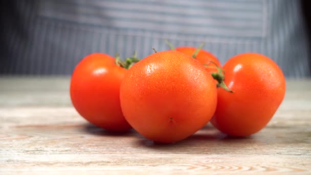 Una rama de tomates rojos maduros se sienta sobre una mesa de madera. Concepto de cocinar platos saludables a partir de verduras frescas — Vídeos de Stock