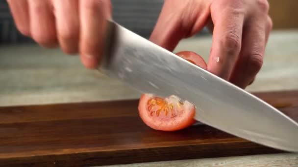 Der Koch schneidet gerade eine reife rote Tomate mit einem scharfen Messer auf einem Schneidebrett. Nahaufnahme — Stockvideo