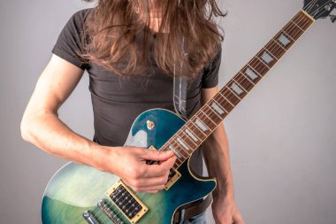 Genç bir adam tek başına gitar çalıyor ve uzun saçlarını sallıyor. Rock 'n Roll' un duygusal performansı