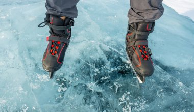 Buz tutmuş bir gölün güzel mavi buzunun üzerinde patenlerin içinde ayaklar. Üst görünüm