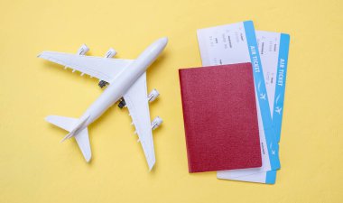 Uçağın minyatürü, uçak biletleri ve sarı arka planda pasaport. Seyahat, tatil ve bilet rezervasyonu kavramı.