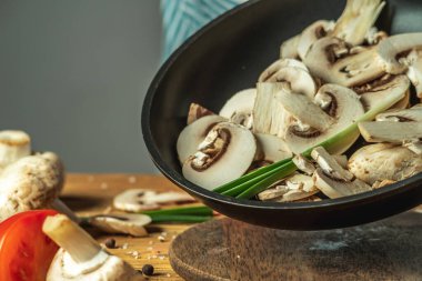 Taze kesilmiş mantarlar, aşçının ellerinde kızartma tavasında. Yemek pişirme süreci kavramı.