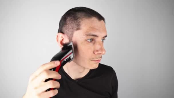 A fickó levágja a haját egy ollóval a kamera előtt. Rövid férfi frizura otthon — Stock videók
