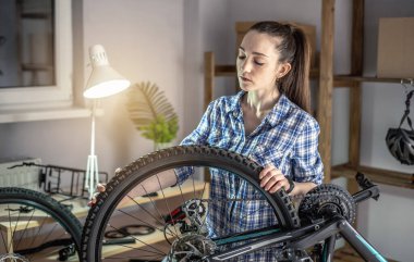 Bir kadın dağ bisikletinin bakımını yapıyor. Bisikleti yeni sezon için tamir etme ve hazırlama kavramı