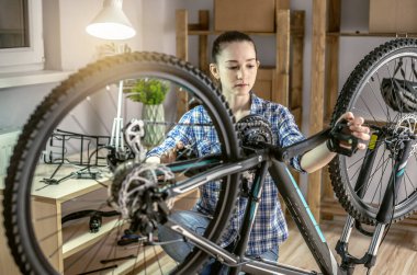 Atölyedeki bir kadın bisikletini söküyor ve tamir ediyor. Yeni sezon için bakım ve hazırlık kavramı