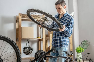 Bir adam dağ bisikletinin bakımını yapıyor. Bisikleti yeni sezon için tamir etme ve hazırlama kavramı