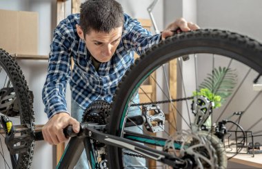 Bir adam dağ bisikletinin bakımını yapıyor. Bisikleti yeni sezon için tamir etme ve hazırlama kavramı