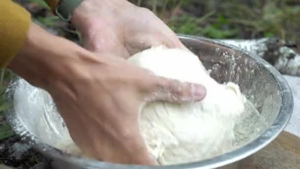 Erkek eller şenlik ateşinde ekmek yapmak için ormandaki hamuru yoğuruyor. Doğada yemek pişirme kavramı — Stok video