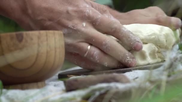 Las manos masculinas están amasando la masa en el bosque para hacer pan en la hoguera. Concepto de cocina en la naturaleza — Vídeos de Stock