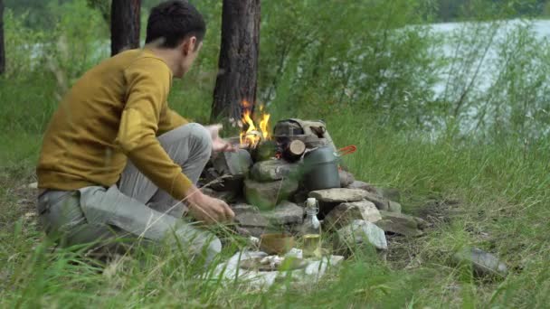 Muž v lese u ohně krájí zeleninu na vaření. Pojem přežití dovednosti v divočině, pěší turistika — Stock video