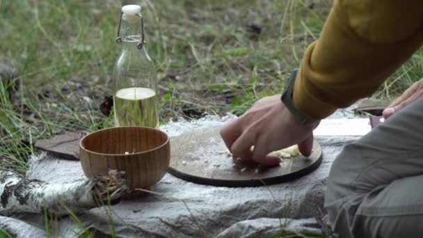 火で森の中の男は料理のために野菜を切っている。野生での生存技術の概念,ハイキング — ストック動画
