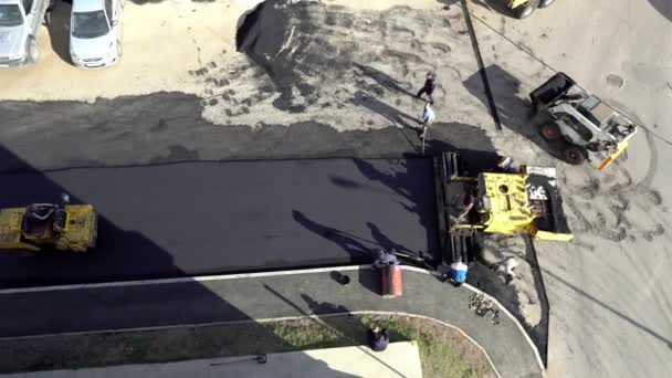 Arbetarna lägger en ny asfaltbeläggning med varm bitumen. Arbete med tunga maskiner och vägläggare. Ovanifrån — Stockvideo