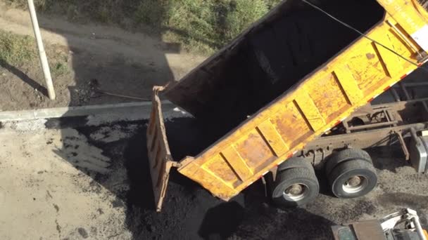 Camión de descarga vierte betún del cuerpo para la colocación de asfalto nuevo. El trabajo de maquinaria pesada y una pavimentadora de asfalto — Vídeo de stock