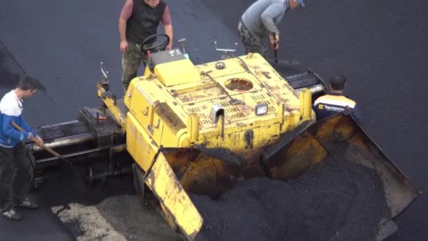 Los trabajadores ponen un nuevo recubrimiento de asfalto utilizando betún caliente. Trabajo de maquinaria pesada y pavimentadora. Vista superior — Vídeo de stock