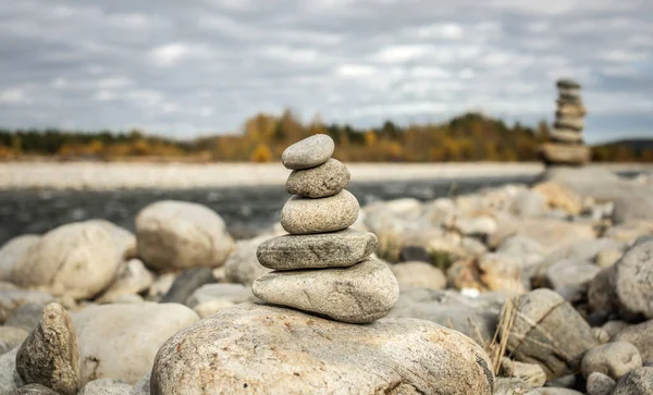 Pile of stones built in cairn on the background of river. Concept of calmness and detachment with nature