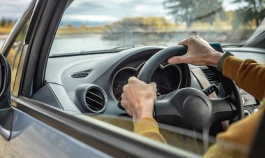 Sarı kazaklı bir adam nehir boyunca araba sürüyor ve güzel bir sonbahar ormanı. Doğa kavramı, seyahat ve sonbahar havası. Yakın çekim.