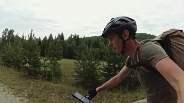 Turysta rowerowy jeździ rowerem po drodze na tle drzew poza miastem — Wideo stockowe