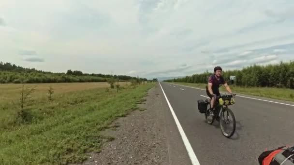 Escursionista ciclista va in bicicletta sulla strada sullo sfondo di alberi fuori città — Video Stock