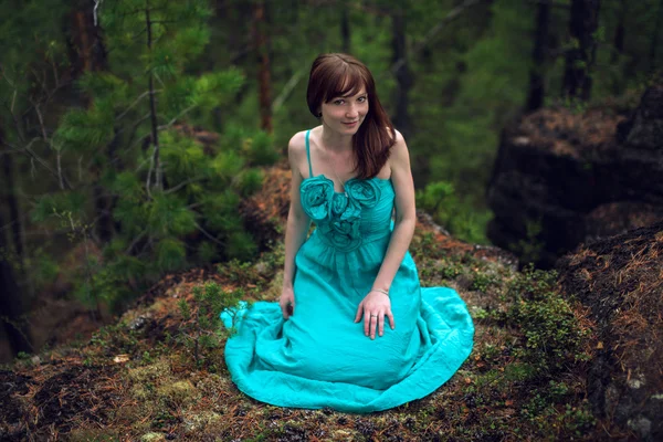Mulher bonita sentada em uma rocha na floresta — Fotografia de Stock