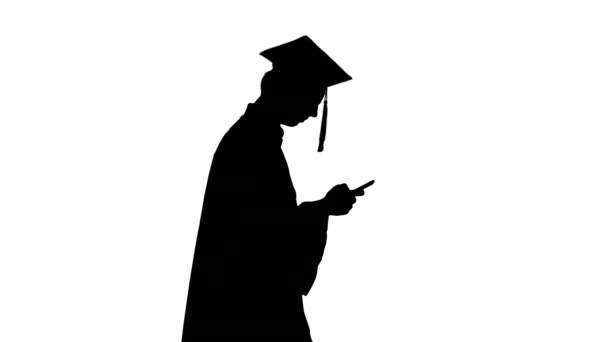 Silhouette Graduate estudiante caminando mensaje de texto de la mano en el teléfono. — Vídeo de stock