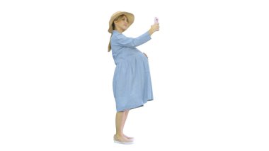 Şapkalı mutlu hamile kadın akıllı telefonunu kullanarak selfie çekiyor.