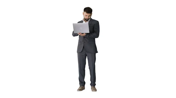 Hombre de negocios guapo de pie y trabajando en el ordenador portátil en blanco bac — Foto de Stock