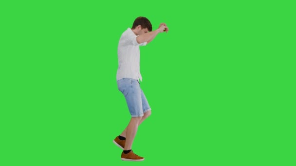 Mladý muž v neformálním oblečení tančí šťastně při chůzi na zelené obrazovce, Chroma Key. — Stock video