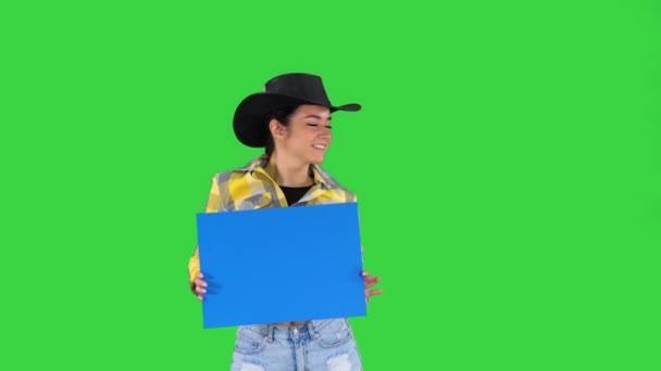 Senyum koboi cantik memegang papan kosong dan menari di Layar Hijau, Chroma Key. — Stok Video