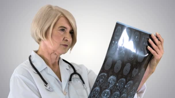 Старша медична лікарка Жінка, яка дивиться на Мані на градієнтному фоні. — стокове відео