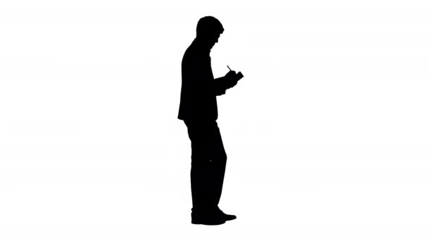 Silhouette Pensando hombre de negocios escribir notas en su cuaderno mientras camina. — Vídeo de stock