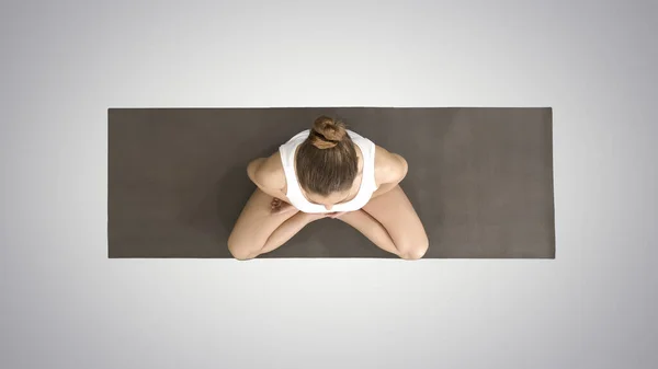 Kvinna i vit praktiserande yoga i lotus poserar på lutning backgro — Stockfoto