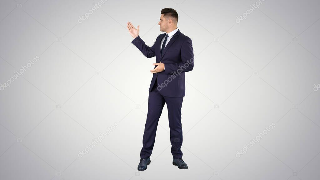 Smiling businessman pointing on something and talknig on gradien