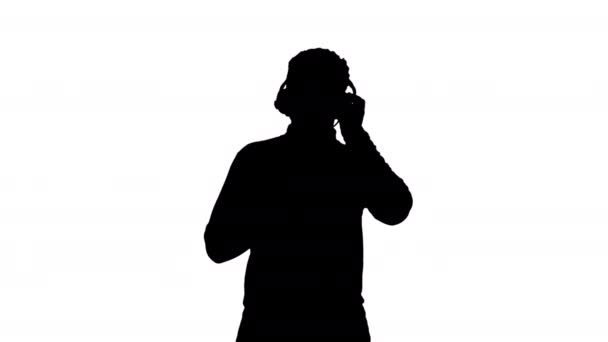 Silhouetteスマイリングアフリカ系アメリカ人男性のヘッドフォンで音楽のリズムに移動. — ストック動画