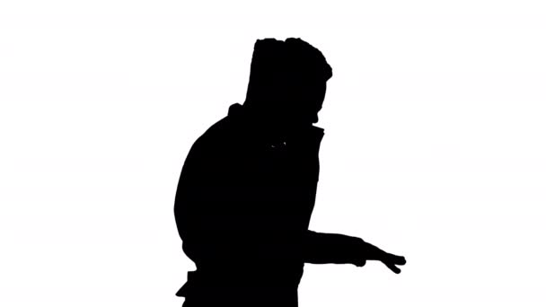Silhouette若いアフリカ系アメリカ人の男性は、ヘッドフォンで音楽を聞いて歩きながらグルーブ. — ストック動画
