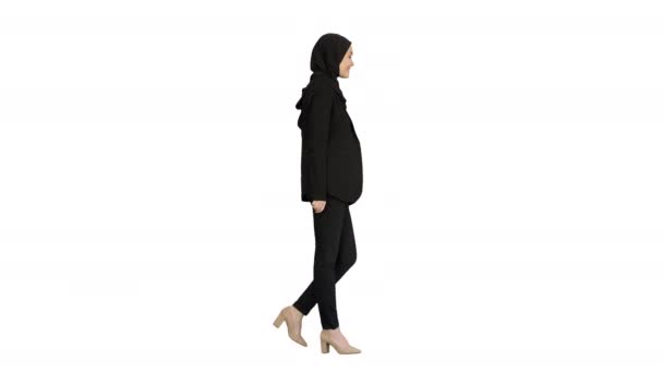 Sonriente modelo femenina islámica con hijab caminando y mirando hacia el futuro sobre fondo blanco. — Vídeo de stock