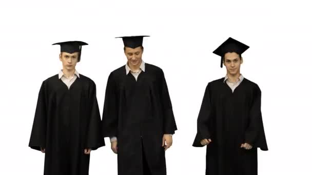 Een mannelijke student in afstuderen badjas en mortel boord beginnen te dansen, terwijl zijn vrienden zijn niet in de stemming voor het op witte achtergrond. — Stockvideo
